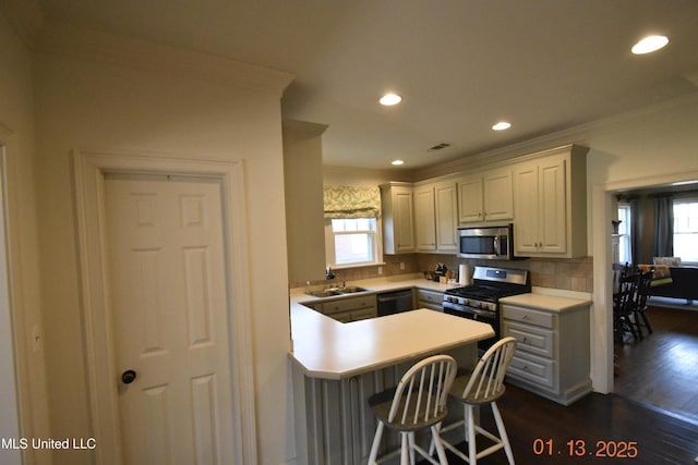 kitchen with stainless steel appliances, kitchen peninsula, dark wood-type flooring, a kitchen bar, and decorative backsplash