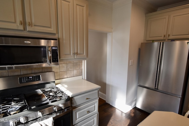 kitchen with cream cabinets, ornamental molding, backsplash, dark hardwood / wood-style flooring, and appliances with stainless steel finishes