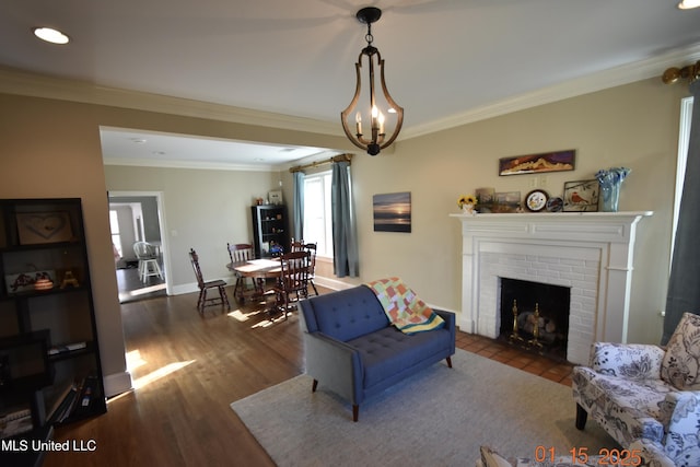 living room with ornamental molding, a notable chandelier, dark hardwood / wood-style floors, and a fireplace