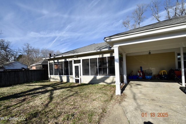 back of property with a yard, a carport, and a sunroom