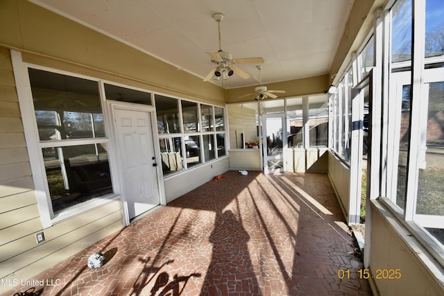 unfurnished sunroom featuring ceiling fan and plenty of natural light