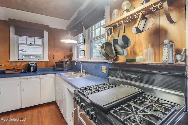 kitchen featuring decorative backsplash, white cabinets, dark wood-style floors, stainless steel gas range, and a sink