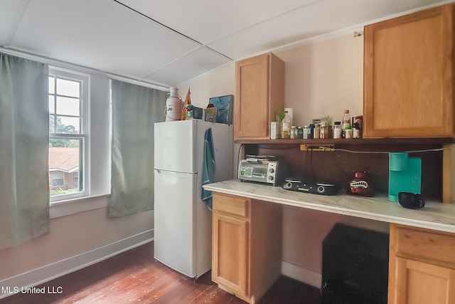 kitchen featuring baseboards, wood finished floors, freestanding refrigerator, vaulted ceiling, and light countertops