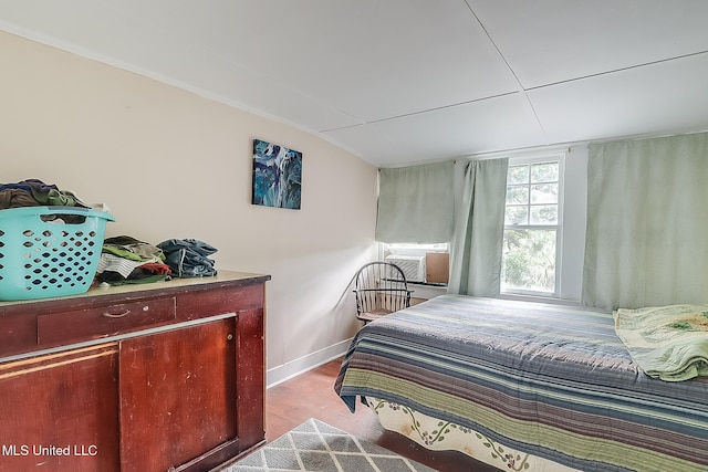 bedroom with cooling unit, vaulted ceiling, baseboards, and wood finished floors