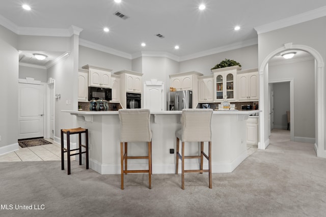 kitchen featuring a center island, black appliances, ornamental molding, tasteful backsplash, and light colored carpet