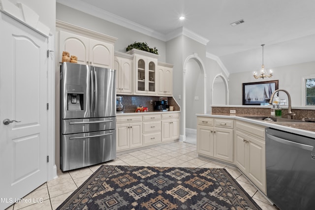 kitchen with sink, hanging light fixtures, ornamental molding, light tile patterned flooring, and stainless steel appliances