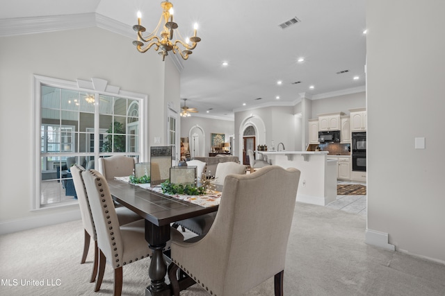 dining area with lofted ceiling, light colored carpet, ceiling fan with notable chandelier, and ornamental molding