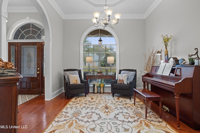 living area featuring crown molding, an inviting chandelier, and hardwood / wood-style flooring