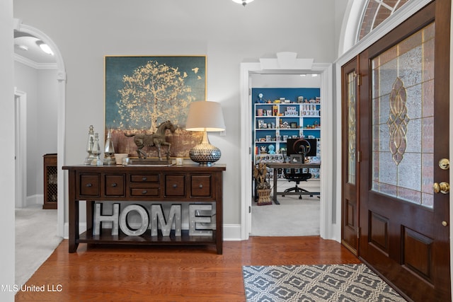 carpeted foyer featuring crown molding