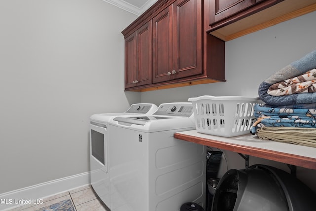 laundry area featuring washer and dryer, light tile patterned floors, cabinets, and ornamental molding