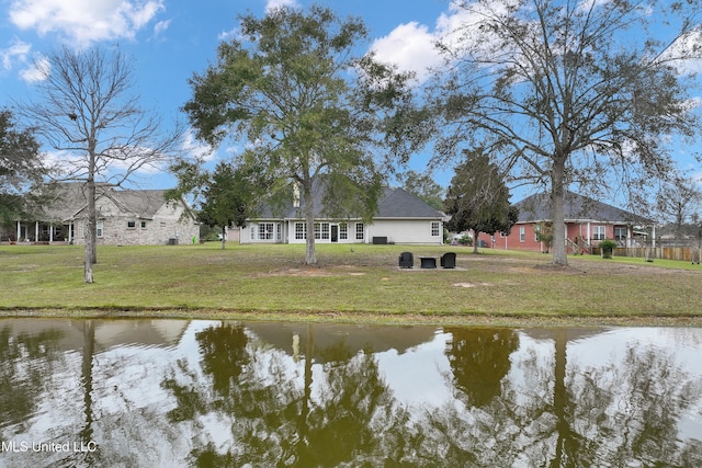 back of property with a water view and a lawn