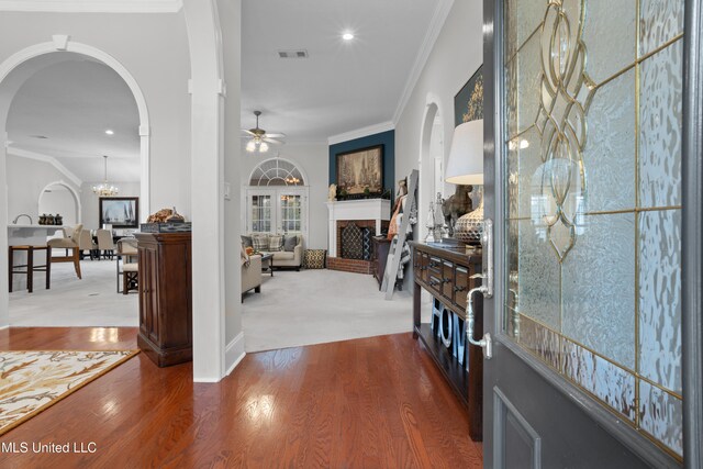 hall with hardwood / wood-style flooring, crown molding, and a notable chandelier