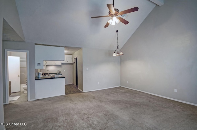 8962 Pleasant Hill Rd, Carthage, MS 39051 - unfurnished living room featuring a ceiling fan, carpet floors, baseboards, high vaulted ceiling, and a chandelier