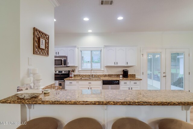 6811 Old Fort Bayou Rd, Ocean Springs, MS 39564 - kitchen with appliances with stainless steel finishes, a sink, a breakfast bar area, french doors, and stone counters