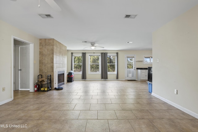 unfurnished living room featuring a wealth of natural light, ceiling fan, baseboards, and visible vents