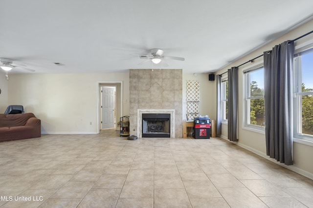 living area featuring baseboards, ceiling fan, a fireplace, and visible vents