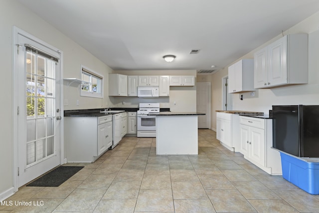 kitchen featuring visible vents, dark countertops, a sink, and white appliances