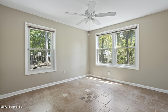 spare room with a healthy amount of sunlight, baseboards, and stone finish floor