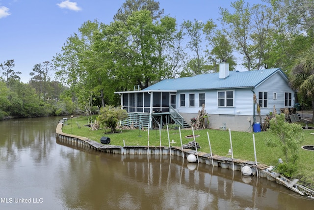 back of house with metal roof, a chimney, a lawn, a sunroom, and a water view