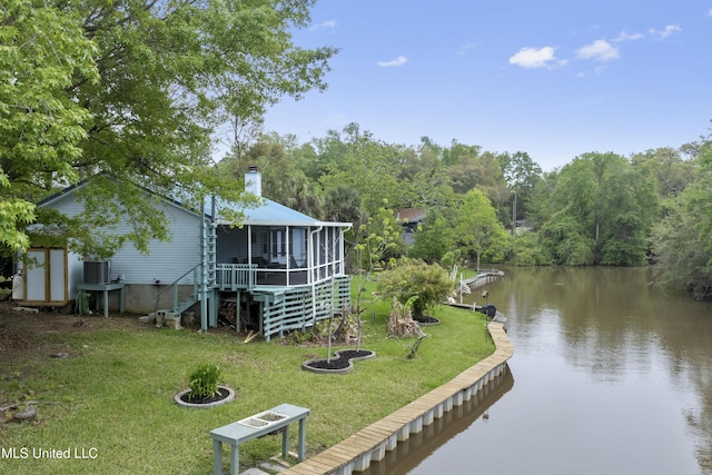 exterior space featuring a lawn, a view of trees, central air condition unit, and a water view