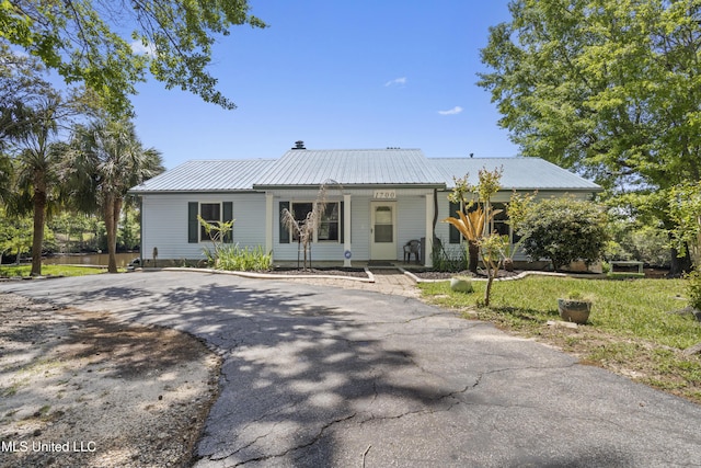 ranch-style home featuring a porch, metal roof, and aphalt driveway