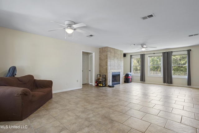 living room featuring baseboards, ceiling fan, a fireplace, and visible vents