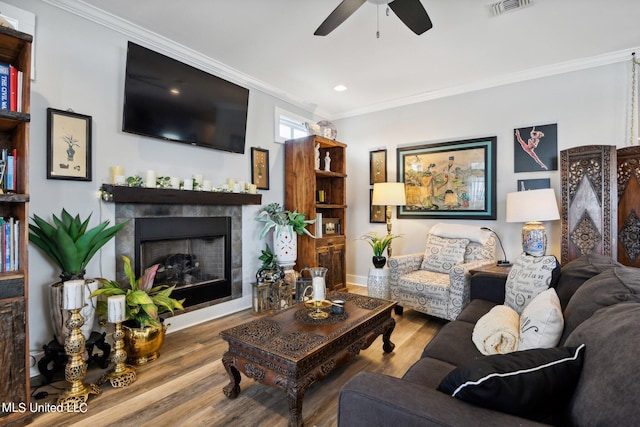 living room with ceiling fan, ornamental molding, a fireplace, and hardwood / wood-style floors