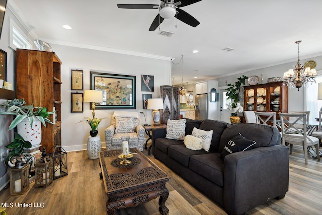 living room with ornamental molding, hardwood / wood-style floors, and ceiling fan with notable chandelier