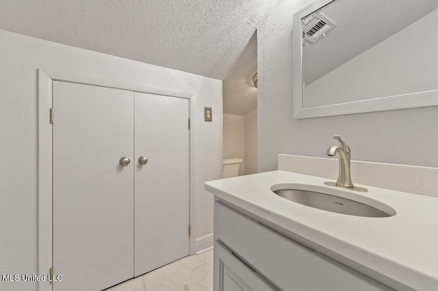 bathroom with vanity, a textured ceiling, and toilet