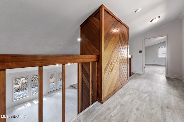 corridor featuring light hardwood / wood-style floors, crown molding, and lofted ceiling