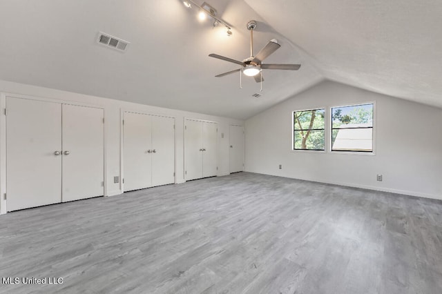 unfurnished bedroom featuring lofted ceiling, two closets, light hardwood / wood-style floors, and ceiling fan