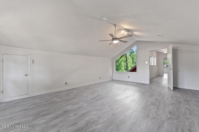 bonus room featuring light hardwood / wood-style floors, ceiling fan, wooden walls, and vaulted ceiling