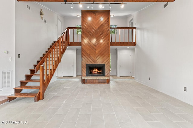 unfurnished living room with ornamental molding, light tile patterned flooring, a fireplace, and track lighting