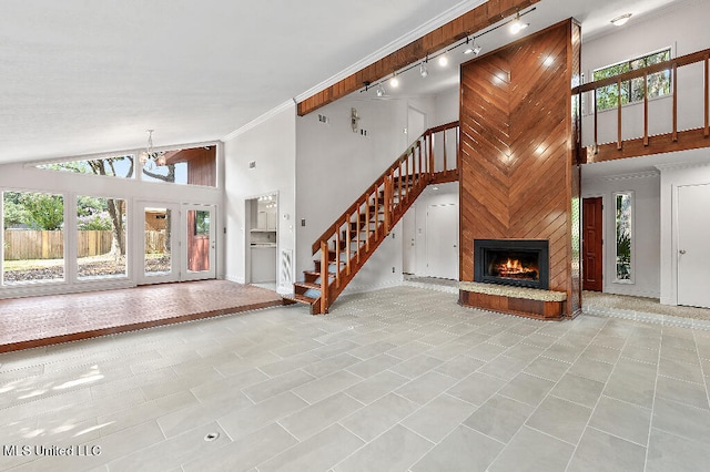 unfurnished living room with high vaulted ceiling, light tile patterned floors, a fireplace, a notable chandelier, and track lighting