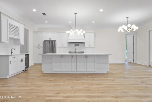 kitchen with an inviting chandelier, crown molding, light countertops, and appliances with stainless steel finishes