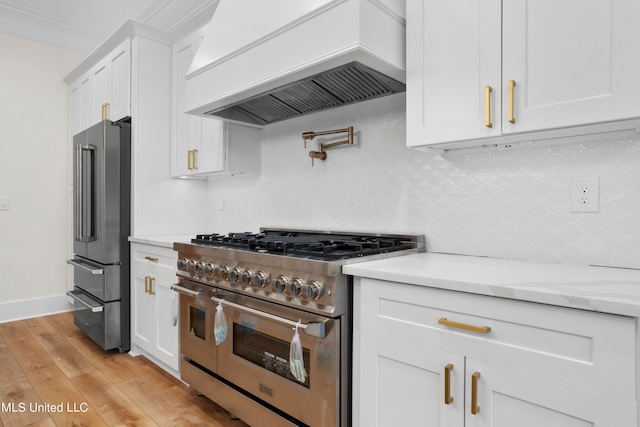 kitchen featuring high quality appliances, white cabinetry, custom range hood, and light wood-type flooring