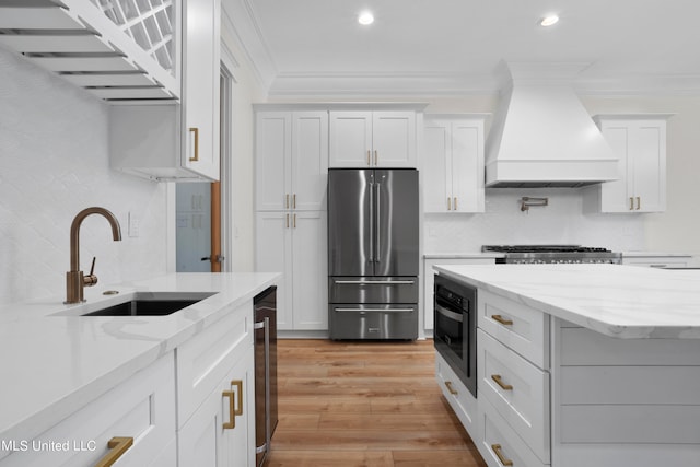 kitchen featuring sink, premium range hood, stainless steel appliances, and white cabinetry