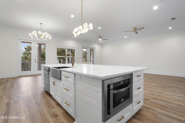 kitchen featuring stainless steel dishwasher, ornamental molding, french doors, and a sink