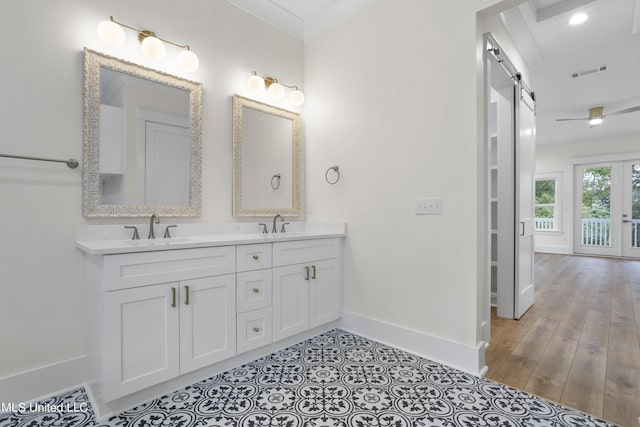 full bath featuring baseboards, visible vents, double vanity, and a sink