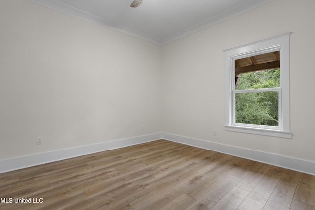 empty room with crown molding, baseboards, and light wood-style flooring