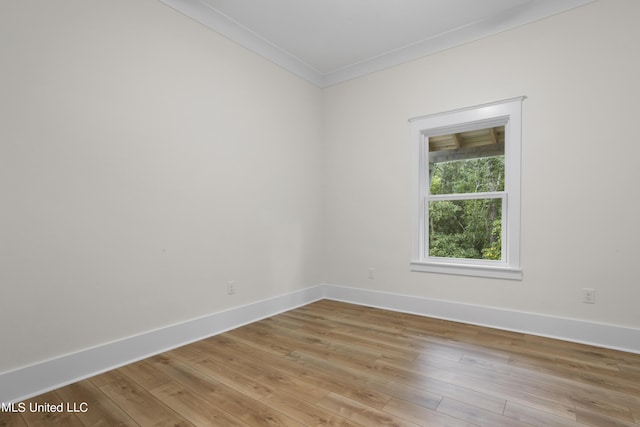 spare room featuring baseboards, light wood-style floors, and crown molding