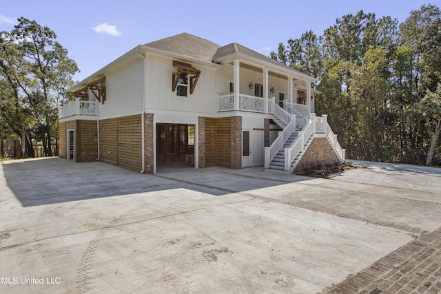 view of front of house with a porch, stairs, brick siding, driveway, and a carport