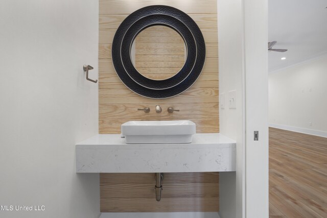 bathroom with wood finished floors, a sink, baseboards, ornamental molding, and recessed lighting