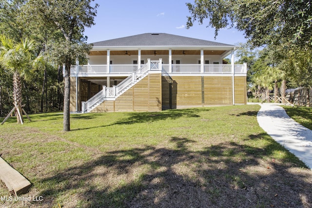 rear view of property featuring a lawn, stairway, roof with shingles, and ceiling fan