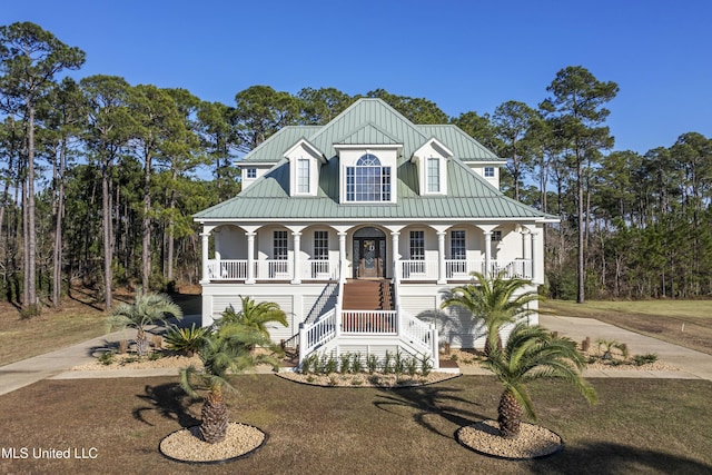 view of front of house with stairway, a standing seam roof, covered porch, driveway, and metal roof