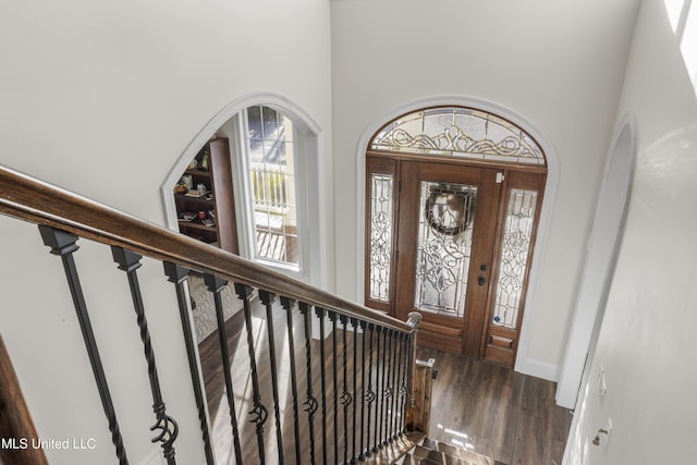 foyer featuring baseboards, stairs, a towering ceiling, and wood finished floors