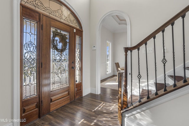 foyer entrance featuring crown molding, stairs, baseboards, arched walkways, and dark wood finished floors