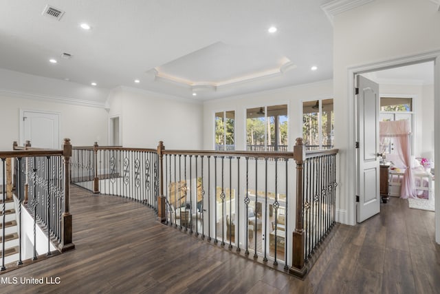 hall featuring crown molding, a tray ceiling, visible vents, and wood finished floors