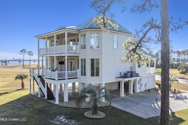 view of front of property featuring stairs, ceiling fan, a balcony, driveway, and metal roof