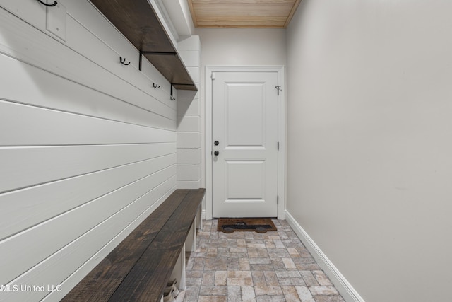 mudroom featuring wooden ceiling, baseboards, and brick floor